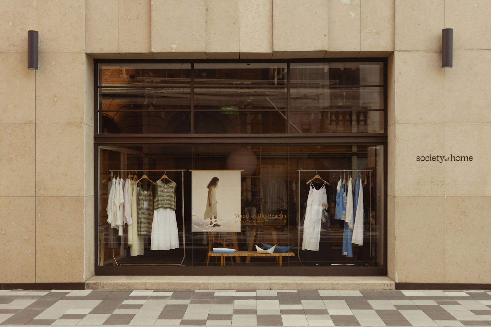 A clothing store window display with mannequins and racks